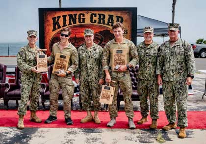 The official party poses for a photo with the winners from Explosive Ordnance Disposal Mobile Unit 2, Explosive Ordnance Disposal Technician 1st Class Nick Wiencek and Explosive Ordnance Disposal Technician 3rd Class James Vosler at the King Crab 2026 awards ceremony on Naval Amphibious Base Coronado, California, August 28, 2026. King Crab is the Navy's premier EOD competition, showcasing elite warfighters who specialize in all-domain EOD operations. Over several days, the tactical challenge pushes the physical endurance, technical proficiency, and combat readiness of competitors to ultimately identify the Navy's most capable two-person EOD team. U.S. Navy Photo by MC2 August Clawson. 